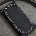 Silver paperclip link chain necklace displayed on black leather handbag background - Silver