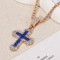 Macro shot of gold cross pendant featuring a deep blue center stone and pavé-set crystals - Cross / Gold Chain with Blue Pendant