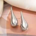 Macro shot of silver teardrop earrings on soft fabric showing sleek metallic texture - Teardrop / Silver Teardrop