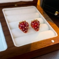 Nahaufnahme von roten Emaille-Erdbeer-Ohrringen mit Golddetails in einer Holzbox - Rote Erdbeere