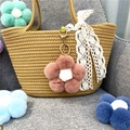 Close-up of a cute pink plush flower pom-pom keychain hanging on a stylish woven bag - 1 Piece / Leather Red