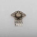 Macro view of vintage bronze leaf hair comb featuring intricate floral openwork pattern - Eye