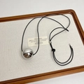 Close-up of polished silver metal sphere pendant on a black cord necklace detail - Metallic Ball Pendant (Z-3127)