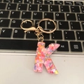 Detail of letter K keychain with colorful heart sequins on a black laptop keyboard - Letter K