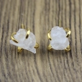 Detail of natural raw white crystal stud earrings with gold claw settings on wood - Clear Quartz