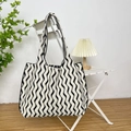 Close-up of black and white wave knit tote bag hanging on a white chair in a minimalist room - Vertical Stripe Beige