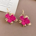 Macro view of orchid earrings with magenta matte petals and golden branch accents - Pink
