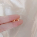 Minimalist 925 silver gold-plated reindeer antler stud earrings held on a fingertip - Moose Antlers / Gold