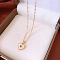 Detailed close-up of heart pendant with green gemstone and gold wave chain in a jewelry box - Heart Style / Gold