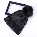 Flat lay view of a black knit beanie featuring a large fluffy pom-pom and ribbed texture - One Size / Black