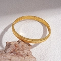 Detalle macro del brazalete bañado en oro de 18k con textura de metal cepillado vertical - Brazalete de anillo cerrado con textura vertical / Dorado