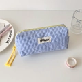Detail of blue and white checkered quilted pencil case with yellow zipper and brand tag - Blue