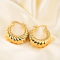 Close-up of 18K gold-plated twisted hoop earrings on light champagne silk fabric - Spiral Croissant Hoop