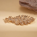 Detailed view of a golden feather brooch with clear rhinestones and a square pendant - Gold