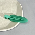 Close-up of a matte green traceless hair clip placed on a white ceramic plate - Lake Blue