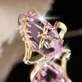 Gold dragonfly ring with pink oval gemstone and leaf detail on a black reflective surface - US 6 / Pink