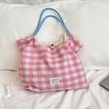 Detailed close-up of pink and white checkered tote bag with blue rope handle on bed - Plaid Pink