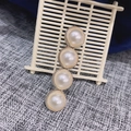 Dettaglio di perle bianche verticali su una base minimalista in metallo dorato - 4 Perle Bianche