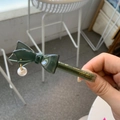 Close-up of a dark green acetate bow hair clip with a pearl drop and brand engraving - Dark Green Bow