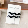 Lot de deux pinces à cheveux noires ondulées en acétate avec base en métal doré chic - Noir 6,8 cm