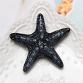 Detailed view of a textured black resin starfish accessory on a white relief plate - Black Starfish