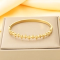 Detail view of 18K gold plated bangle with embossed floral patterns on a display stand - 60*49mm / Four-Petal Flower Relief Style (KB210530-KSZ)