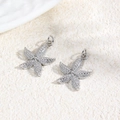 Macro shot of two silver starfish charms with textured metal detail for DIY jewelry - Textured Starfish / Silver