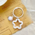 Close-up of white star acrylic keychain with a matching small bell and metal ring - White