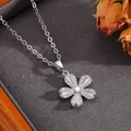 Macro d'un pendentif fleur argenté avec zircons dans une boîte grise avec fleurs séchées - Collier Fleur à Cinq Pétales Argenté avec Zircone (T024)