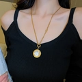 Detail of gold necklace with round white shell pendant and small B letter charm on a model - Gold Number Round Disc
