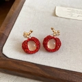 Close-up view of elegant red apple-shaped resin earrings with gold leaf accents - Earrings / Red