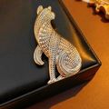 Dettaglio di una spilla a gatto vintage con texture metallica a rilievo su base in pelle - Oro