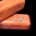 Detailed view of cubic zirconia stud earrings with butterfly back on wood display - 4mm Stud Style (Single) / Steel
