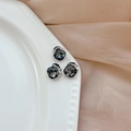 Square dark grey rhinestone earrings with silver metal base shown on a ceramic plate - Transparent Black