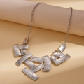 Détail du collier géométrique argenté présentant une texture en métal brossé et des plaques - Argenté