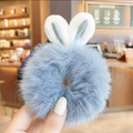 Hand holding a light blue plush scrunchie with white rabbit ears and silver embroidery - Blue Plush Rabbit Ears