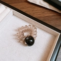Dettaglio dell'elastico a spirale con perla nera su vassoio beige e fondo in legno - Elastico per capelli a spirale cavo telefonico con sfera in acrilico / Nero