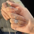 Collier flocon de neige en argent avec zircons brillants tenu délicatement à la main - Flocon de Neige Étincelant / Argenté