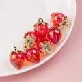 DIY jewelry parts featuring seven red resin strawberry charms with gold metal leaves - Eggplant Red