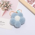 Detalle de llavero de flor de felpa azul y blanca con aro dorado y dije metálico - Flor Azul