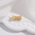 Detailed close-up of a golden bow charm with sparkling pavé zircons on a white tray - Large Bowknot (11.2x6mm) / Gold