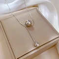 Macro-opname van zilveren titanium Y-ketting met bolletjes en staafje op zijden stof - Zilver