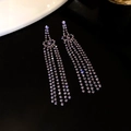 Detailaufnahme funkelnder Strass-Ohrringe mit silbernen Quasten und Fransen-Design - Schwarz-Lila-Hohlherz
