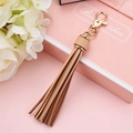 Elegant beige PU leather tassel keychain with a premium golden lobster clasp hanging - Light Coffee