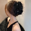 Eleganter schwarzer Feder-Haarclip mit Kristallperlen an einem Frauenhinterkopf - Haarkralle - Schwarze Schleife