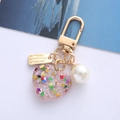 Macro detail of a pink glitter resin heart keychain with gold clasp and pearl charm - Pink