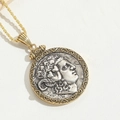 Close-up of vintage bimetal pharaoh pendant with twisted gold chain on white leather - Pharaoh