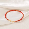 Close-up of red and gold woven rope bracelet with metallic round caps on white silk - Red Gold Spiral