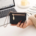 Detail view of black pebble leather wallet with golden leaf zipper and wrist strap - Black