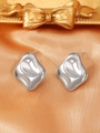 Detailed macro shot of silver fluid-style lava heart earrings on orange satin - Steel Color (K-022)